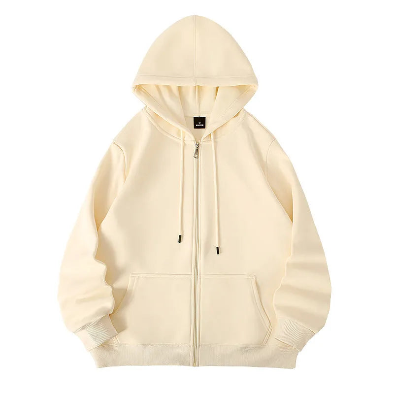 Man wearing a beige heavyweight zip-up hooded sweater, showing top-stitched pockets and loose fit.