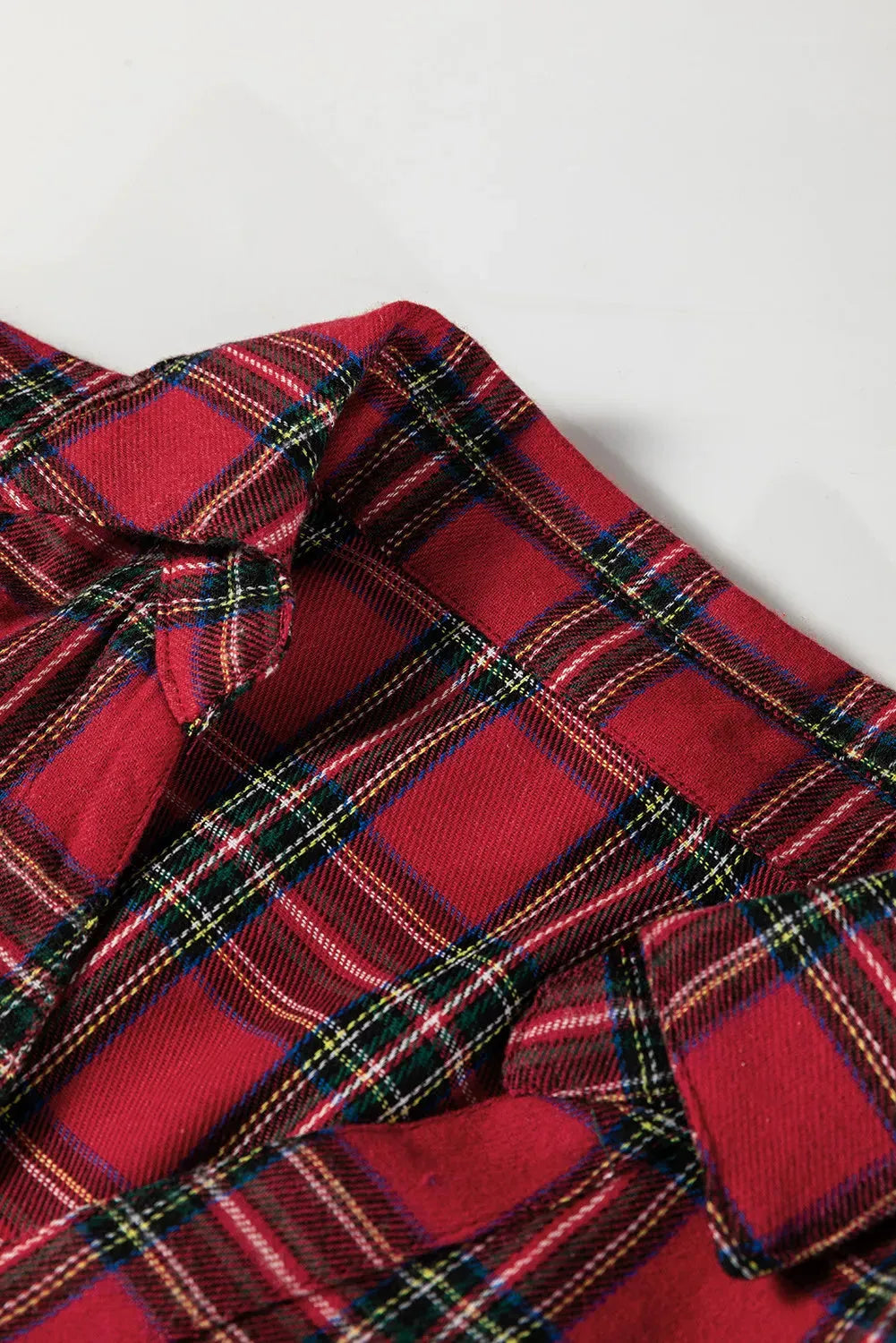 Red plaid mini dress with shirt collar, long sleeves, half-button front, and ruffle hem