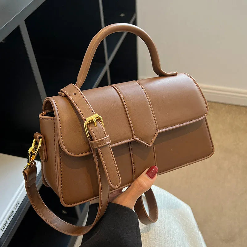 Beige women's square messenger bag with a top handle and shoulder strap, showing an outer pocket.