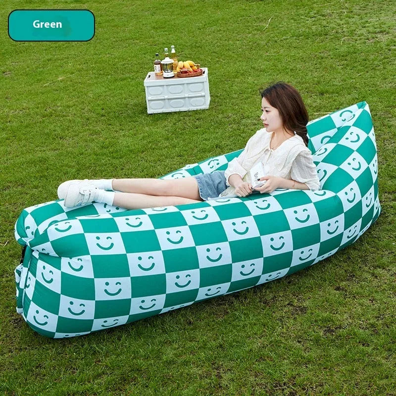 Inflatable portable sofa in a colourful design, shown folded to its 36cm by 27cm size and in use outdoors.