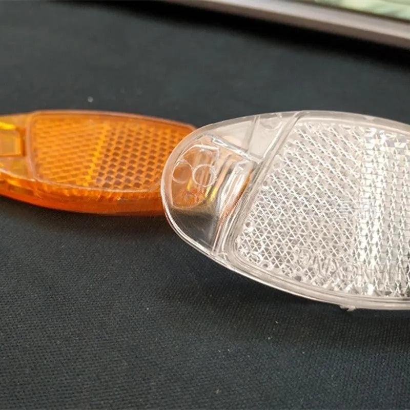 White and yellow plastic bicycle spoke reflector decorations showing front and rear placement on wheel spokes