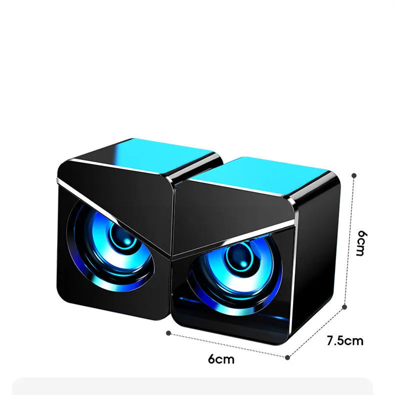 Black and white USB wired mini desktop speaker with volume control next to laptop