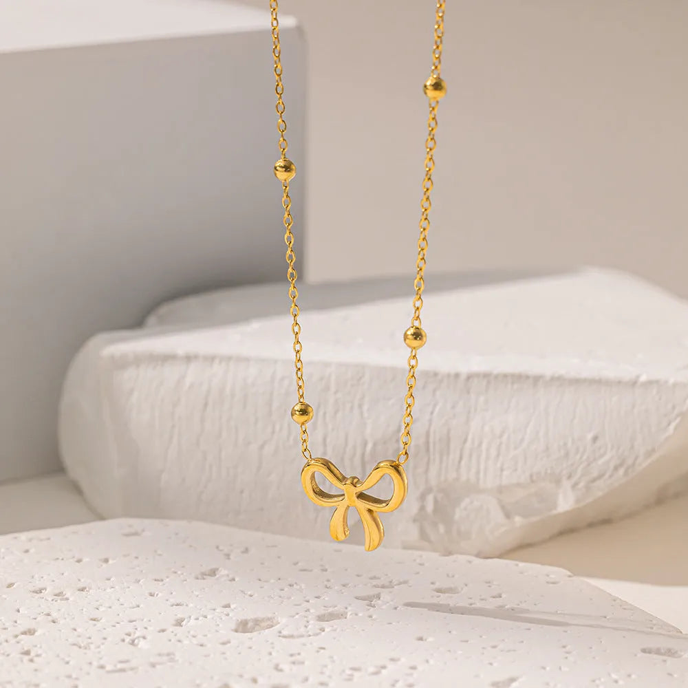 Gold bow necklace on a cross chain, adjustable from 41cm to 50cm length.