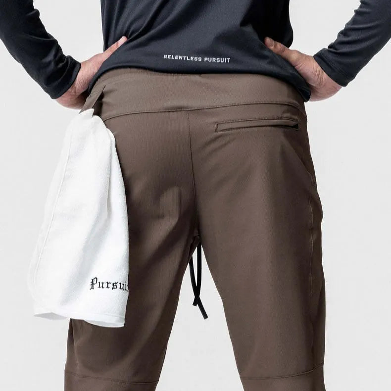 Man wearing dark grey loose-fit ankle-tied fitness trousers made of quick-drying polyester.