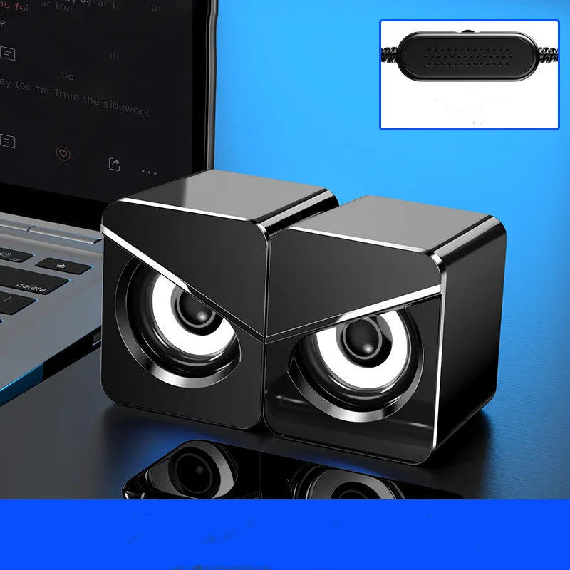 Black and white USB wired mini desktop speaker with volume control next to laptop