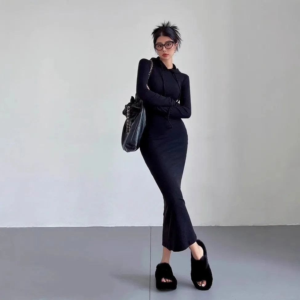 A woman wearing a light grey, long-sleeve polyester sheath dress with an over-the-knee length and high waist.