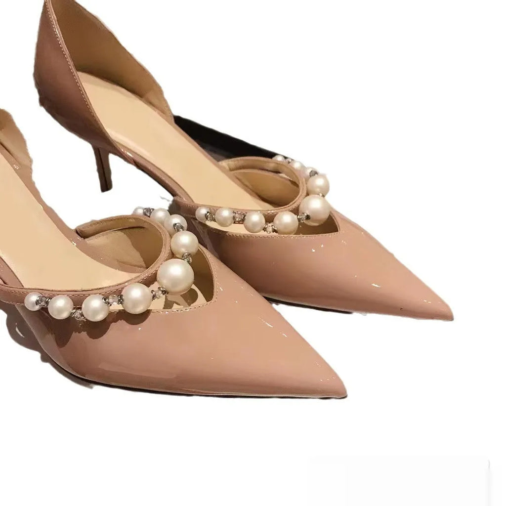 Women's black patent leather stiletto high heels with a pointed toe and pearl decoration on the upper.