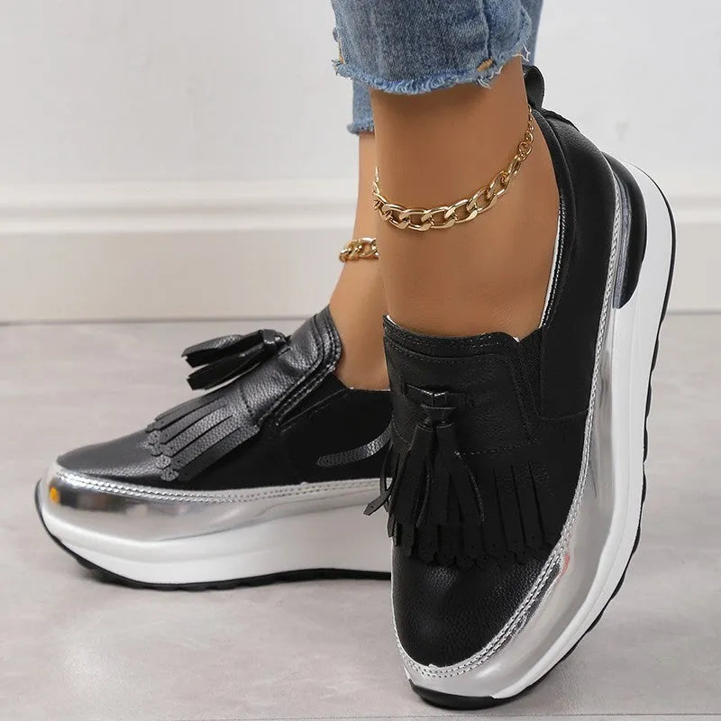 Women's black casual shoes with tassel detail and muffin wedge heel on white background