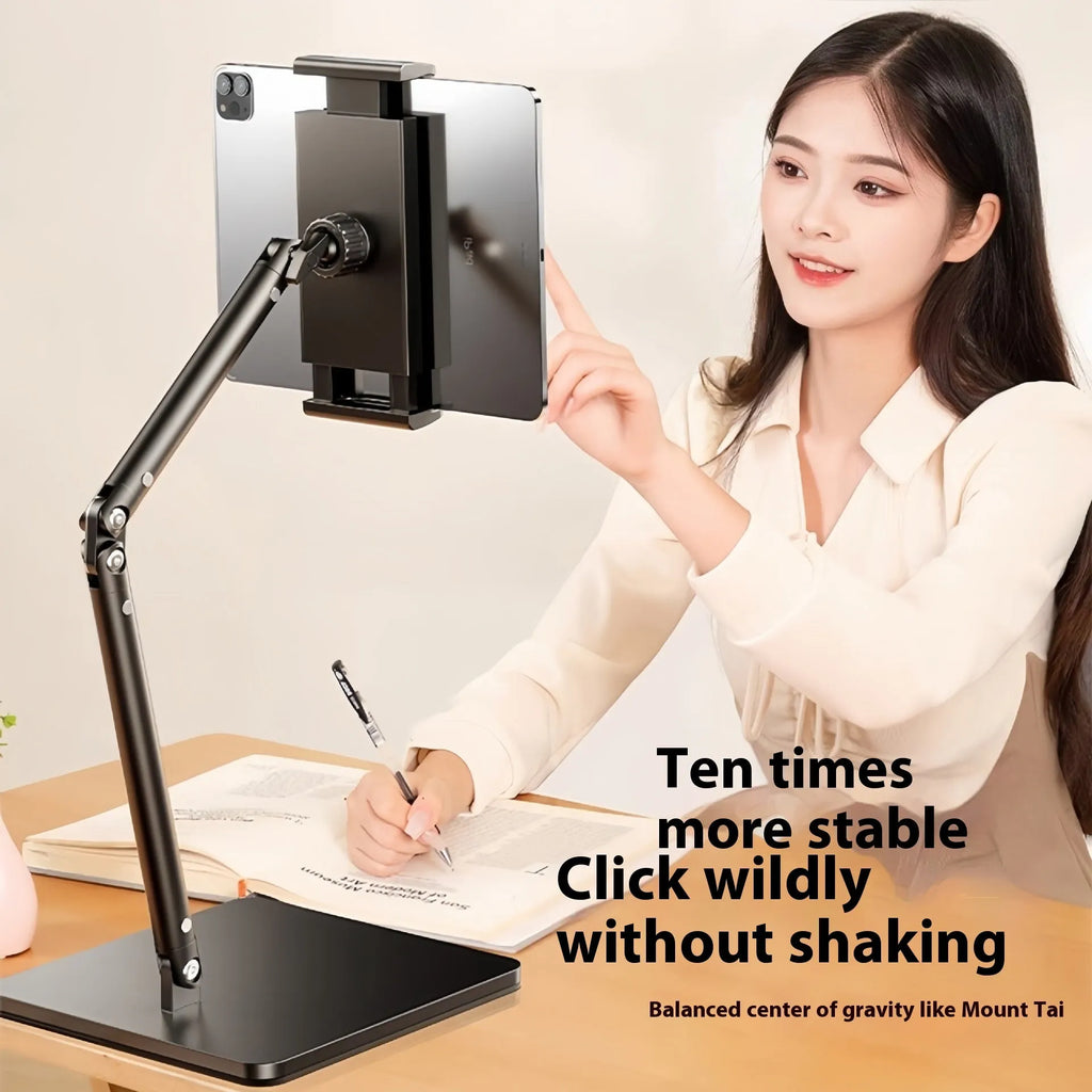Silver alloy desktop phone bracket with double arms holding a smartphone, shown with a remote control on a wooden desk.