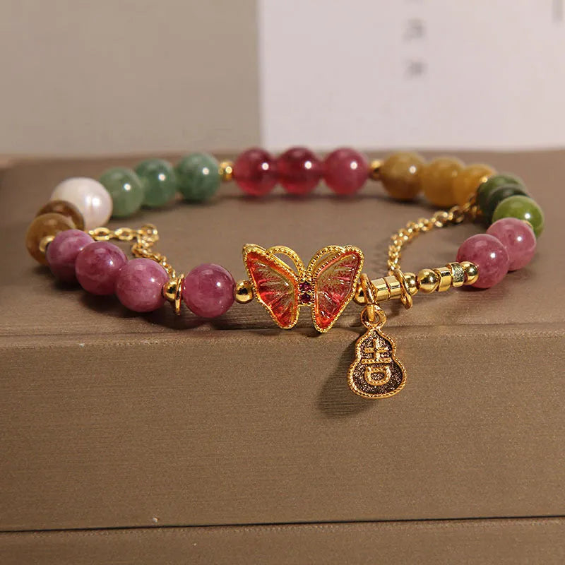Close-up of a women's agate bracelet with a green tourmaline butterfly-shaped gourd charm on a white background.