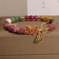 Close-up of a women's agate bracelet with a green tourmaline butterfly-shaped gourd charm on a white background.