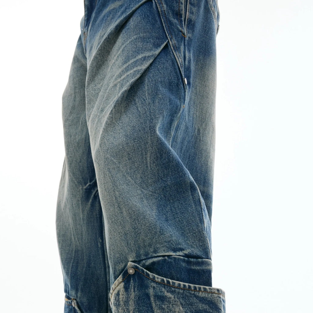 Man wearing loose fit verdant blue retro jeans with a curved knife cut and washed burst pattern.