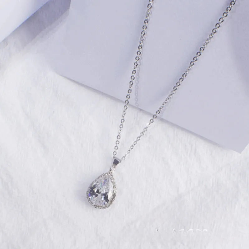 Close-up of a rose gold tone drop shape necklace with rhinestone details on a geometric pendant.