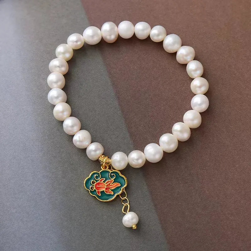 White antique freshwater pearl bracelet with a vintage goldfish and baroque lotus pendant on a chain.