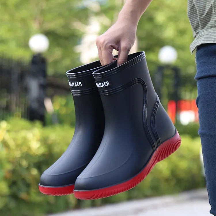 Men's mid-top PVC rain boots in black with green detailing, tassel decoration, and non-slip sole