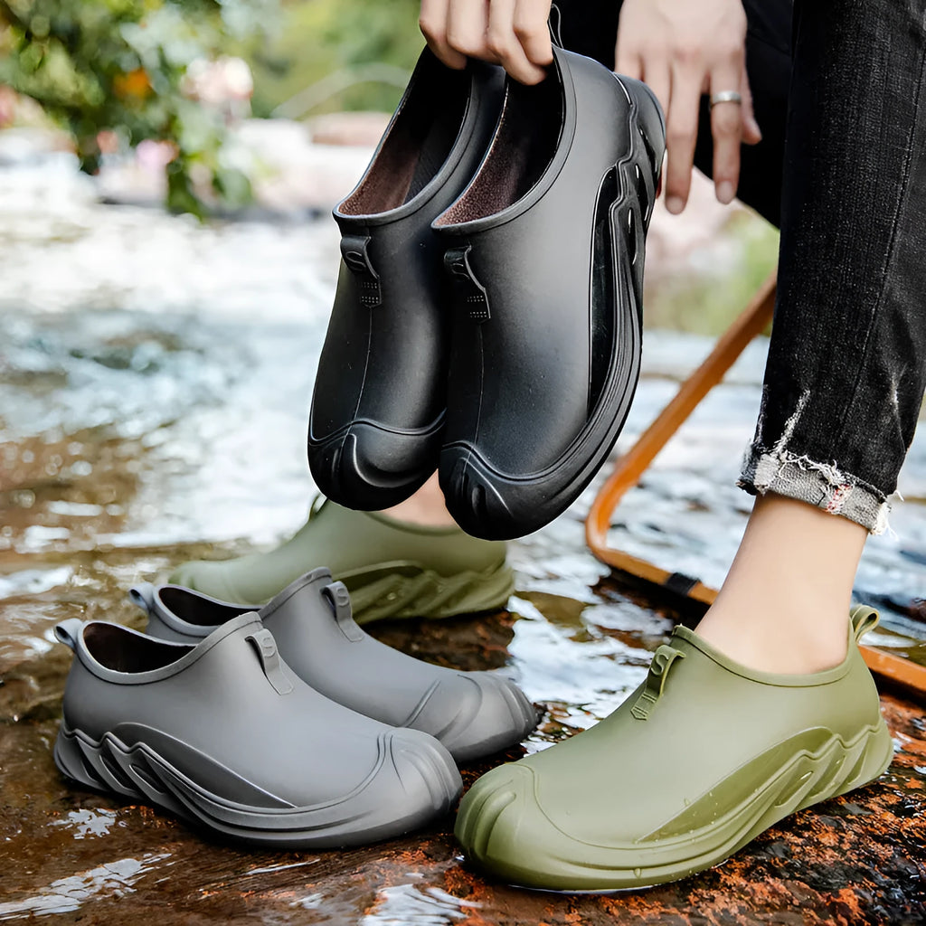 Men's black plastic rain boots on a grey background showing ankle height and solid colour design.
