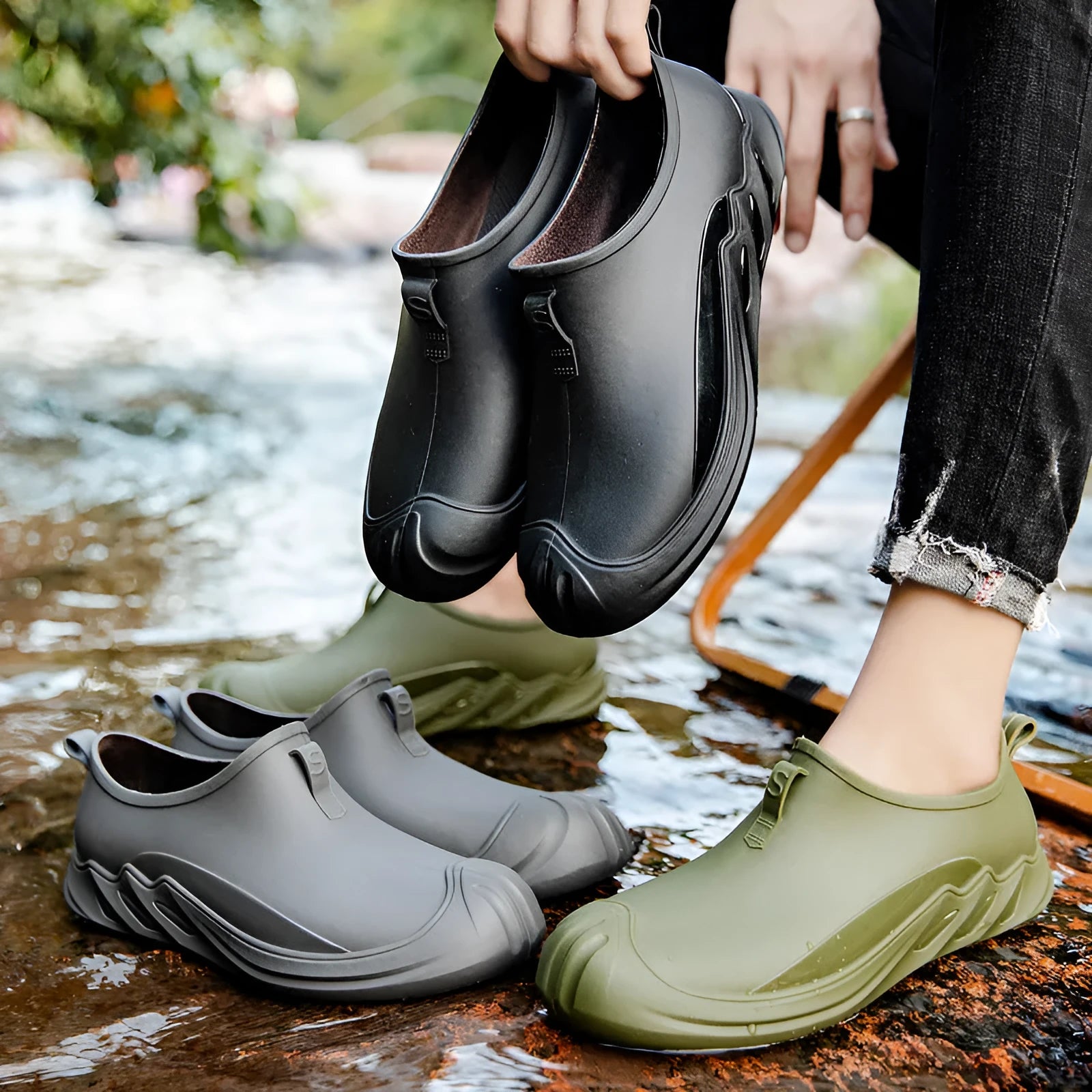 Men's black plastic rain boots on a grey background showing ankle height and solid colour design.