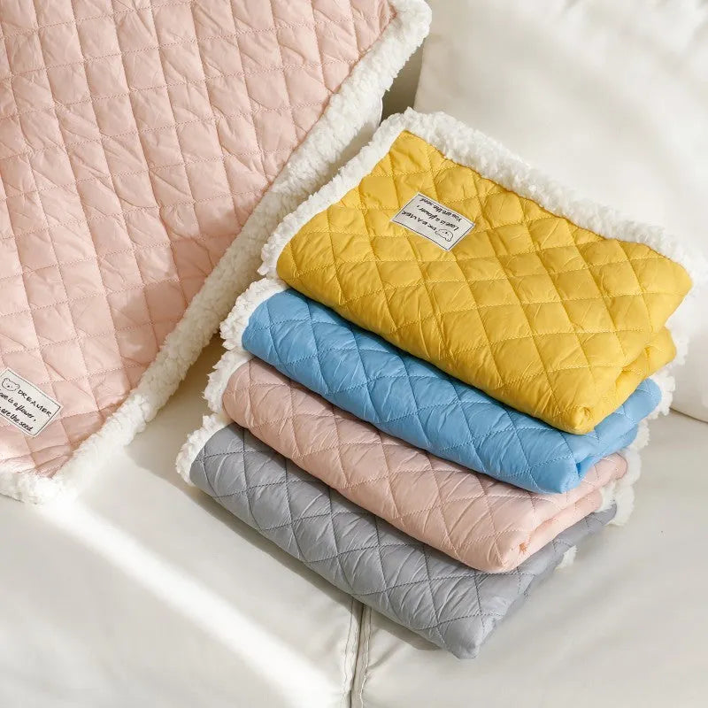 Quilted blue terry cloth pet blanket for cats shown on a pet bed.