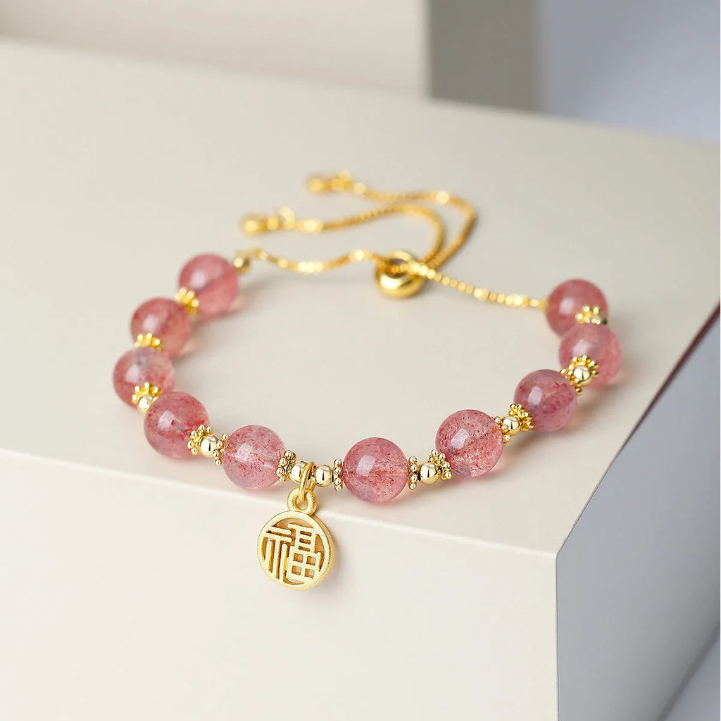 A geometric crystal bracelet in strawberry quartz colour with a fu character detail.