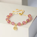A geometric crystal bracelet in strawberry quartz colour with a fu character detail.