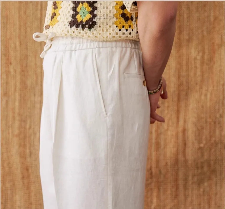 Woman wearing loose-fit linen trousers with a high elasticated waist in a straight-leg cut.