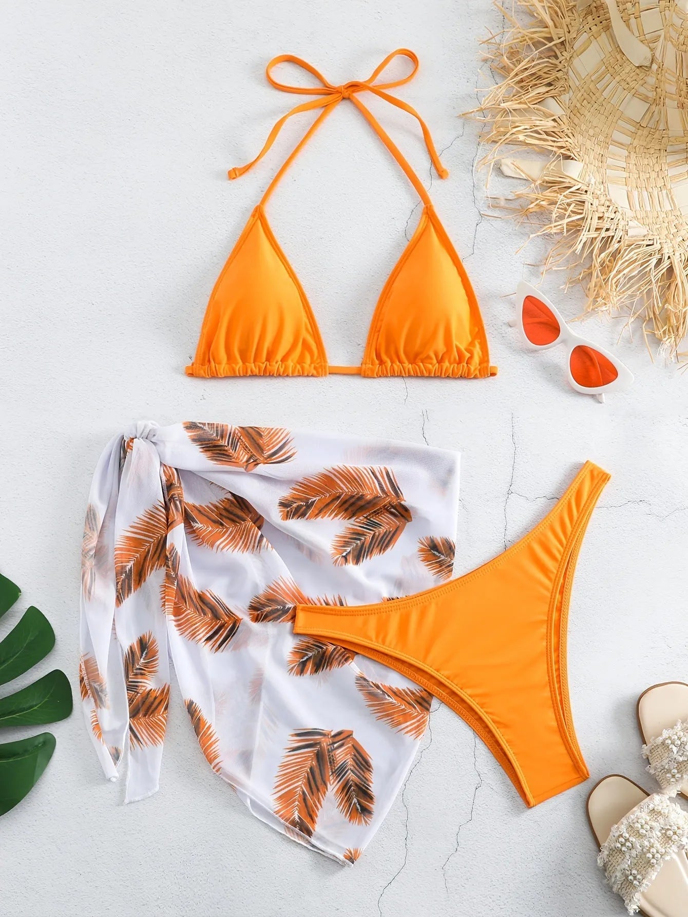 Women's orange three-piece bikini swimsuit set with a matching gauze skirt on a mannequin