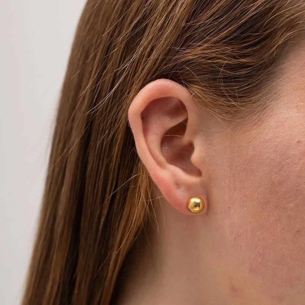 Minimalist round ball stud earrings in gold and silver finishes, showing different size options on a plain background.