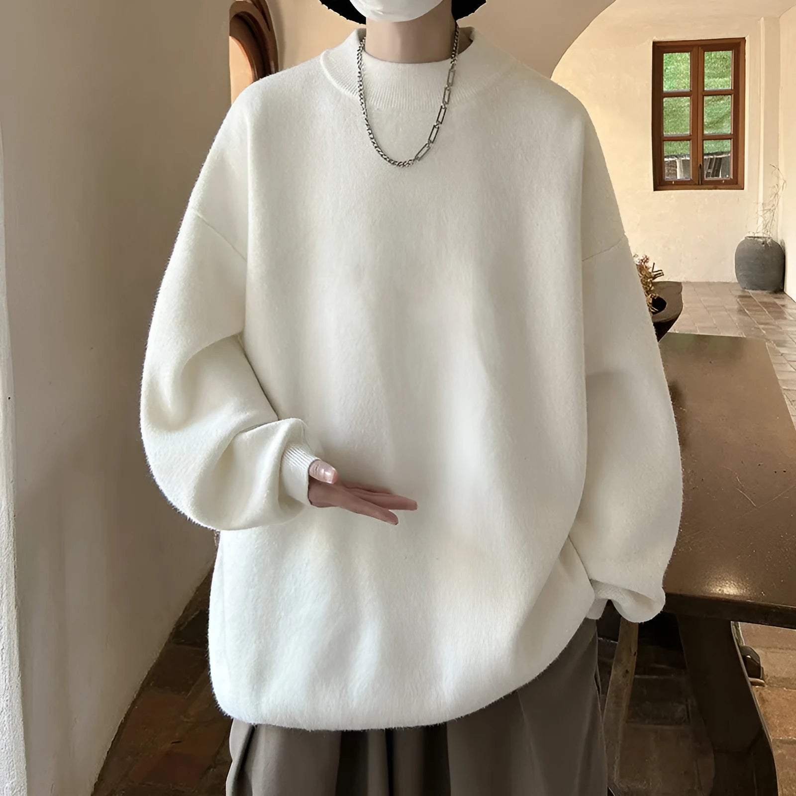 Man wearing a loose fit, solid colour round neck pullover sweater.