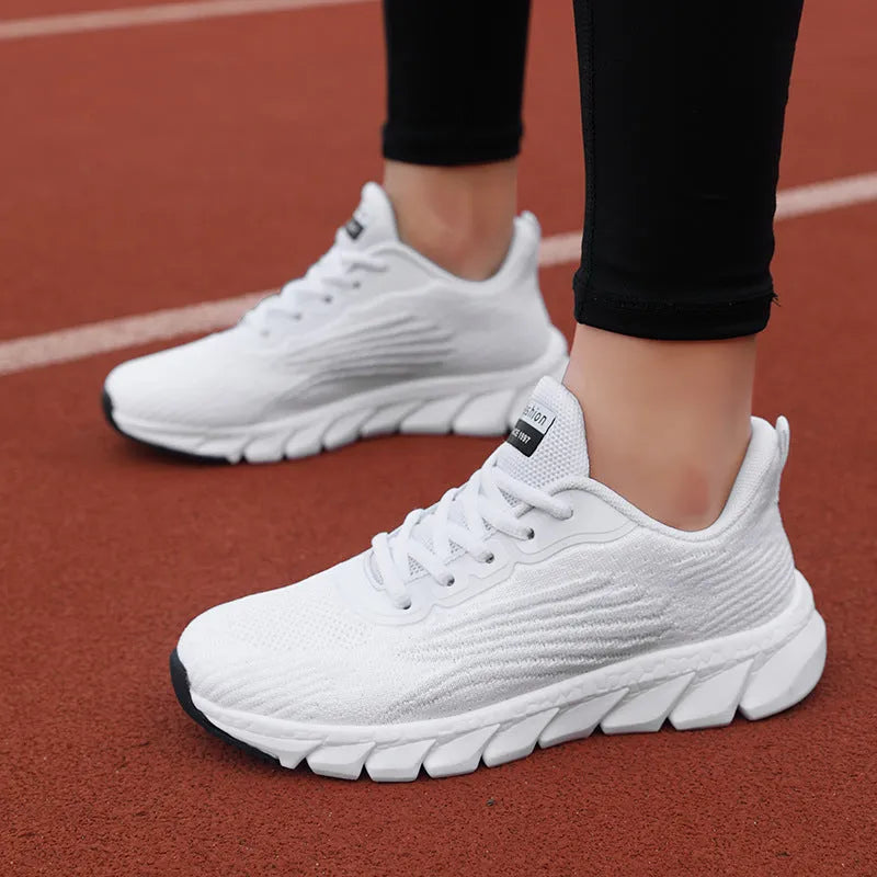 Flat running sneakers with cross-strap detail in black or white colours