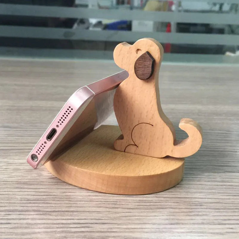 Carved beech wood phone stand with a detailed resin decorative topper, holding a mobile phone upright on a desk.