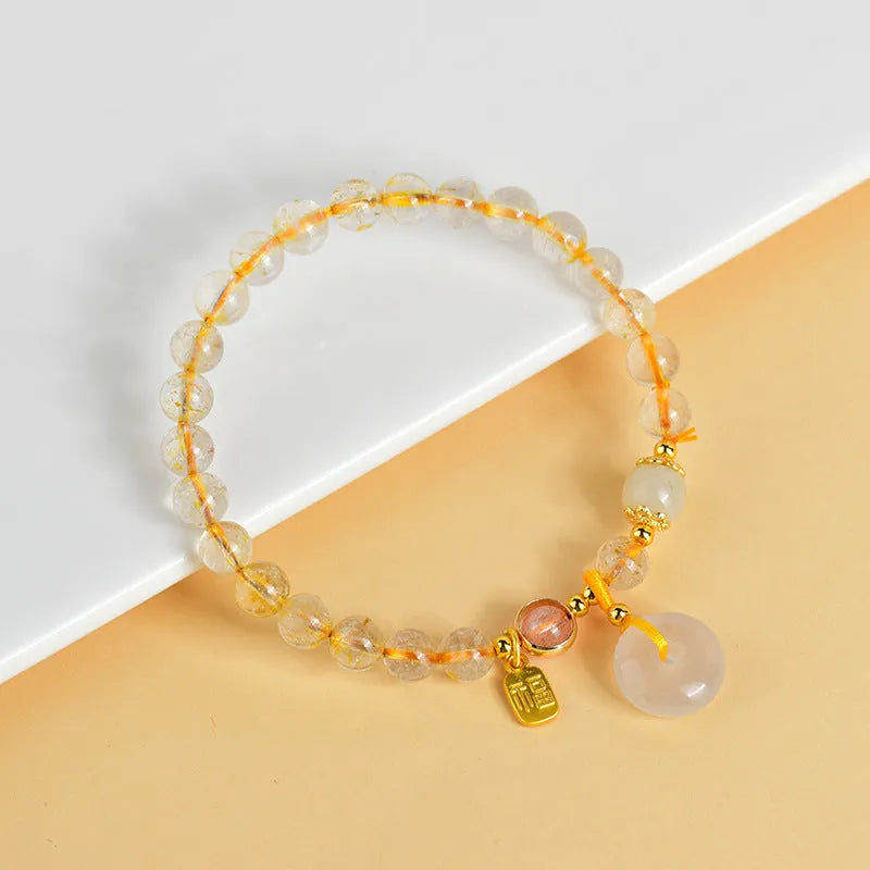 Gold rutilated quartz crystal bracelet with safety buckle and geometric national style design featuring blessing card pendant.