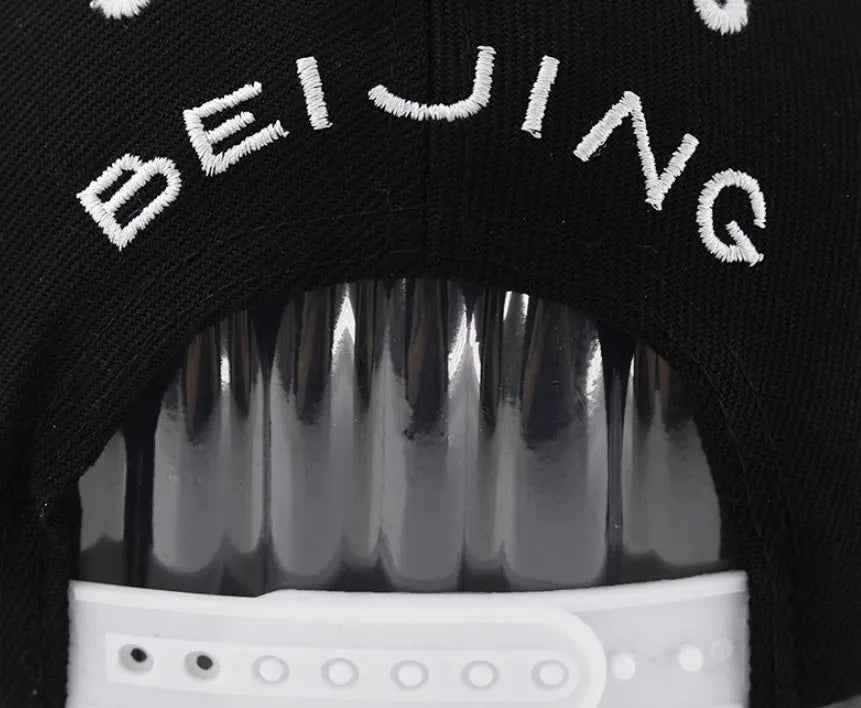Black and white cotton baseball cap with embroidered letter design on the front.