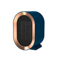 Compact black desktop ceramic fan heater with mechanical dials on a wooden desk.
