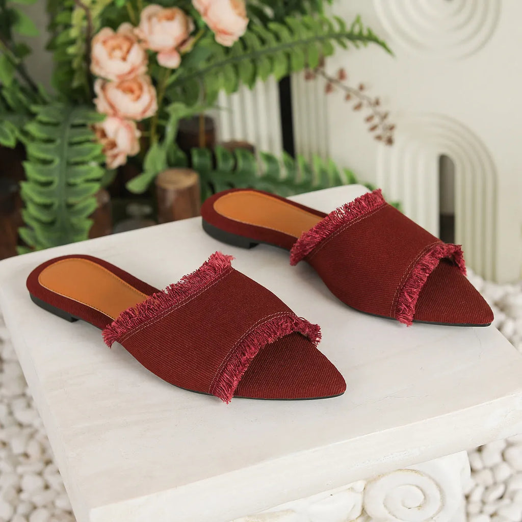 Women's denim slippers with tassel detail and leather lining in various colours on a flat PVC sole.