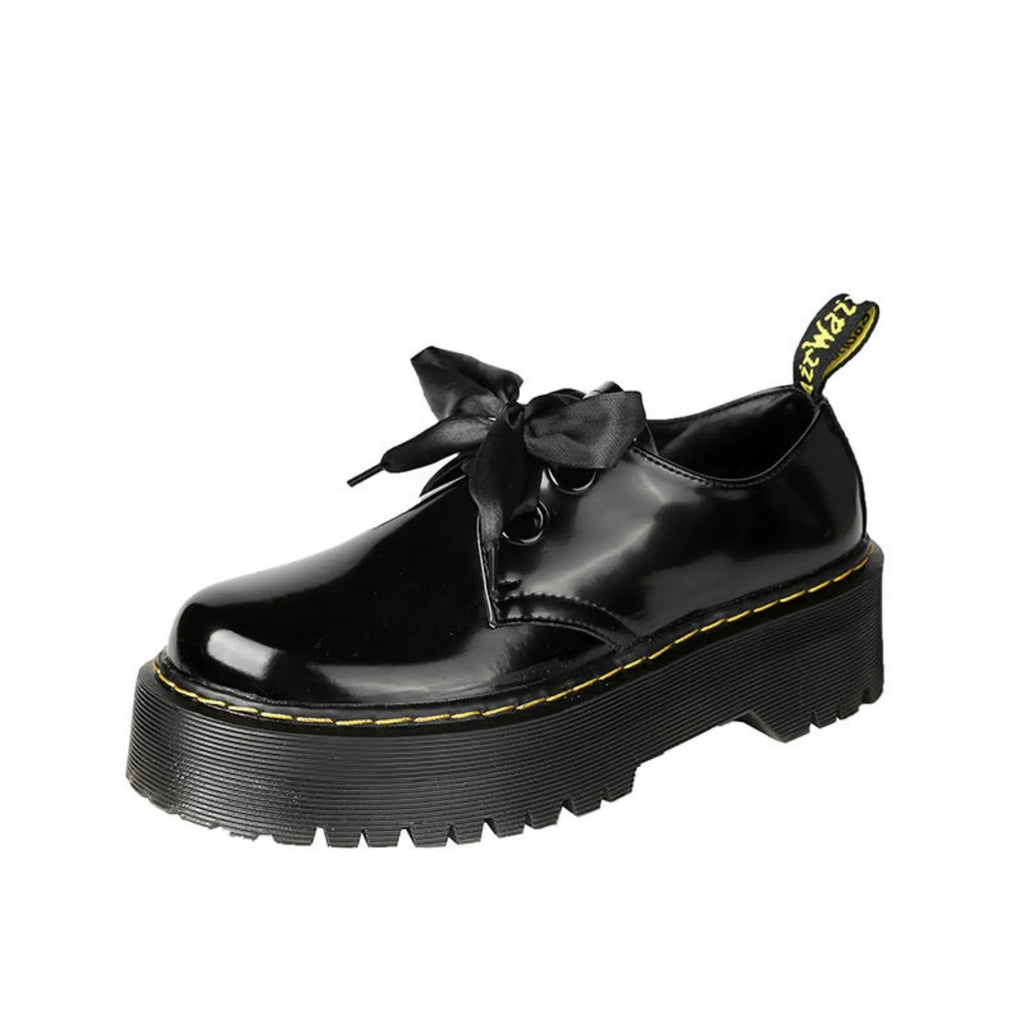 Women's black leather flat shoes with thick soles, cross straps, ribbons, and laced closure.