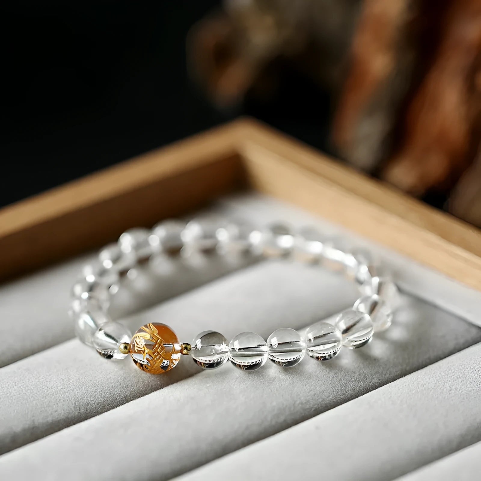 Geometric obsidian and white crystal bracelet with a golden dragon charm on a wrist.