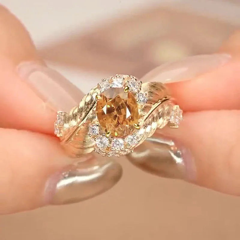 Gold-coloured copper ring with an embossed geometric feather pattern and inlaid yellow zircon stones.