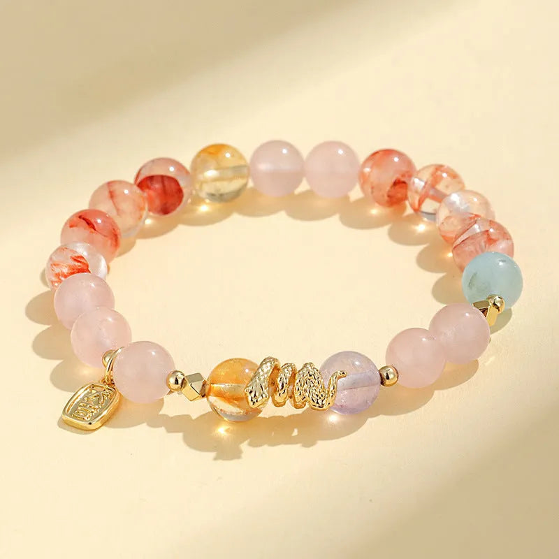Handmade women's crystal string bracelet with lucky snake charm and coloured beads on wrist.
