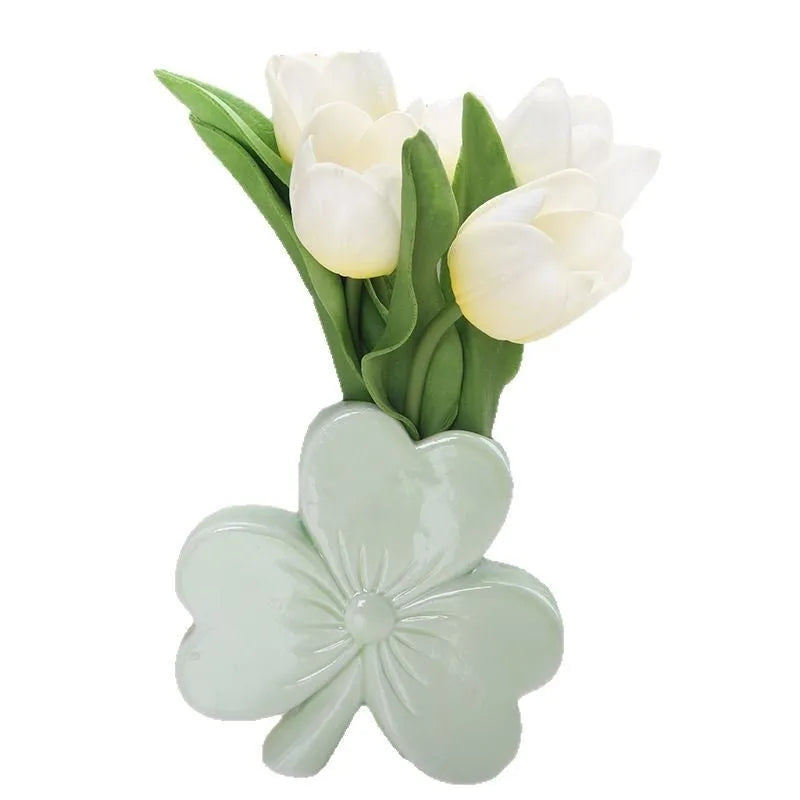 White porcelain clover-shaped ceramic vase in European style, on a desktop.