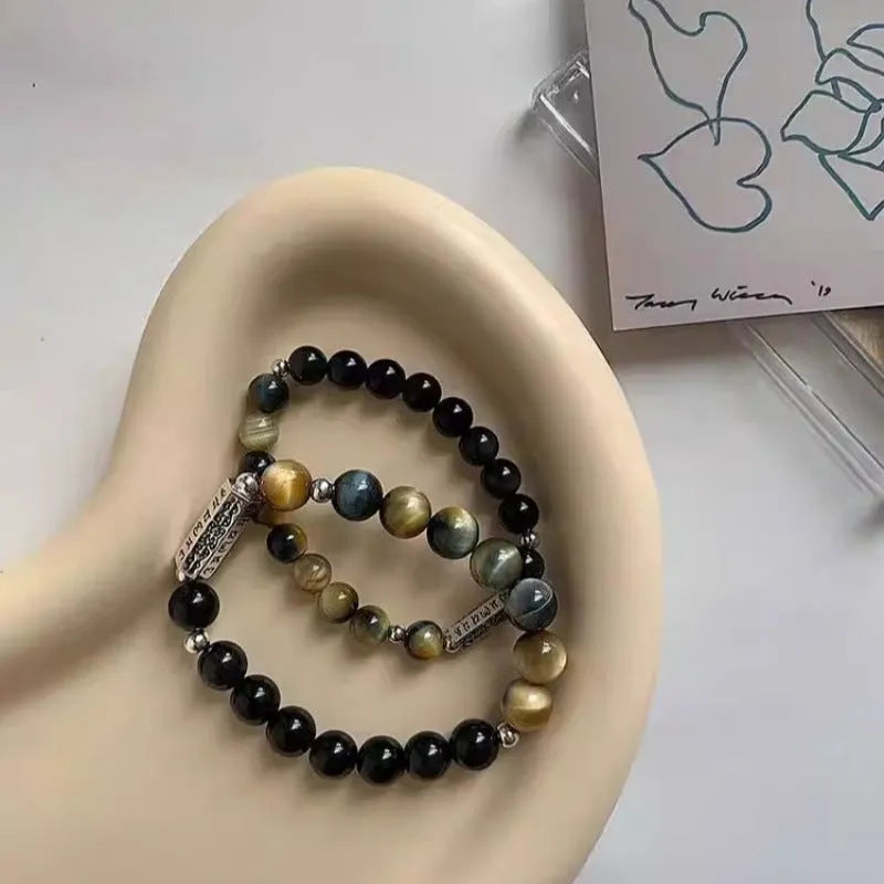 Sterling silver bracelet with obsidian and tigereye stone beads showing geometric round design and mantra engraving